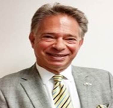 A person wearing a suit and tie smiling at the camera

Description automatically generated