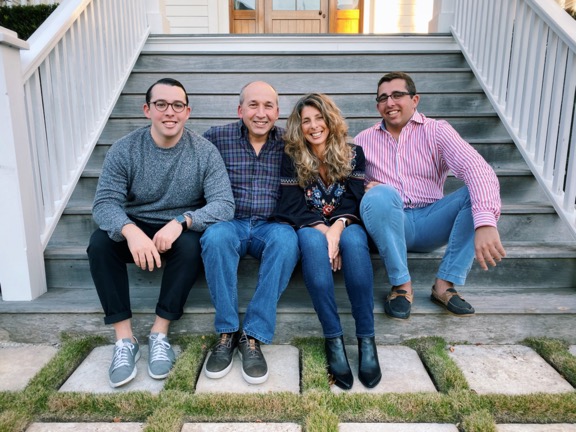 A group of people sitting on a bench posing for the cameraDescription automatically generated